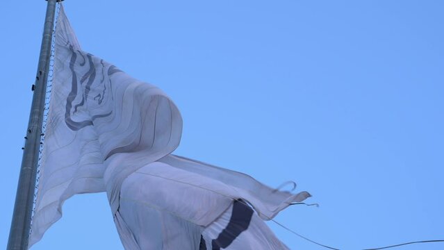Close-up of frayed Taliban Afghan flag moving in wind by blue sky