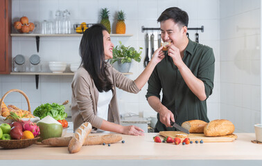 Attractive Asian young sweet couple cooking together in home kitchen. Beautiful woman smiling...