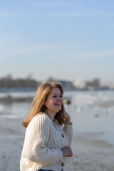 Smiling young woman in knitted sweater running at beach