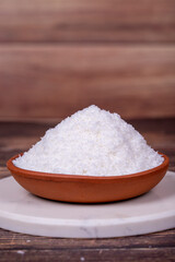 Grounded coconut flakes on wooden background. Coconut shavings in clay bowl. Close up