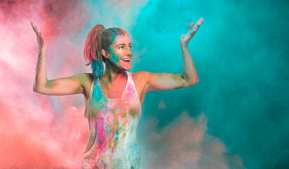 Carefree cheerful woman covered in rainbow colored powder celebrating the festival of colors. Young...