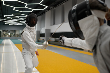 Two young swordsmen in uniform practicing attack and defense during training
