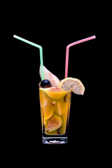 Pieces of tropical fruits in a glass with a plastic straw