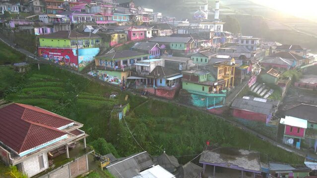 Aerial view of motorcycle cross in the middle of countryside. Morning activity on the Butuh Village Nepal Van Java. Motorists deliver climbers to the Mount Sumbing climbing post - 4K aerial view