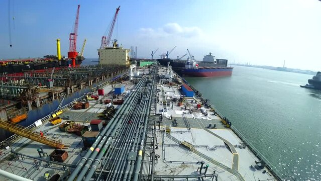 ship repair at the shipyard, the ship is near the pier, people walk on the deck. The work of dock cranes, cranes move along the pier, Daylight
