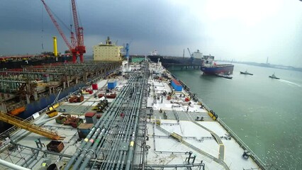 ship repair at the shipyard, the ship is near the pier, people walk on the deck. The work of dock cranes, cranes move along the pier. A ship is moored in the background