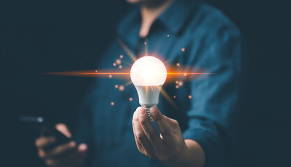 Man hand holding bright light bulb with graph economic