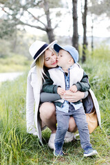 Pregnant woman with kid outdoors. Mother and her son on nature in spring forest. Little child boy...