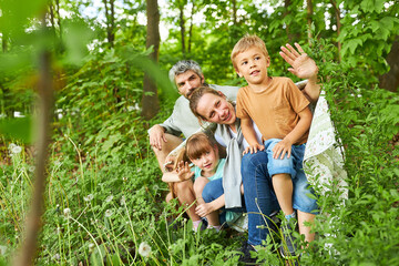 Family exploring in green forest during summer holiday