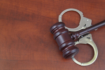 Wooden gavel and handcuffs on table. Copy space for text.