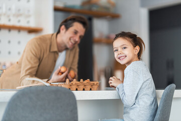 Portrait of a cute little girl sitting at the kitchen table with her father.