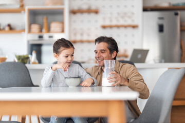 Happy father and daughter enjoying their breakfast time, little girl eating cereals with milk.