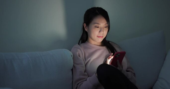 Woman use of mobile phone at night on sofa