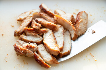 Grilled and sliced chicken breast on white cutting board.