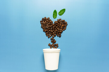 Ein Pappbecher mit Kaffeebohnen in Herzform auf einem blauen Hintergrund. Symbol, Flat lay.