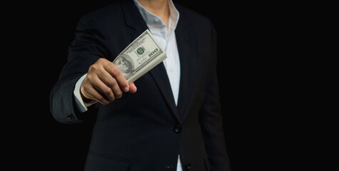 Businessman holding US dollar bills while standing on a black background