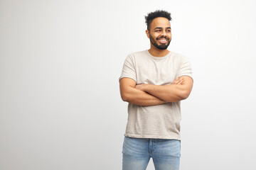 young pensive afro american guy in t-shirt stands on white isolated background and looks to the side