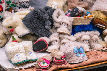 Warm slippers for children. Slippers for the home made of yarn for children. Multicolored knitted slippers. Products made of natural wool. Warm clothes for winter on the market.