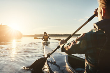 Kayak, lake and people rowing a boat on the water during summer for recreation or leisure at sunset. Nature, view and horizon with people canoeing for adventure, freedom or travel while on vacation - obrazy, fototapety, plakaty