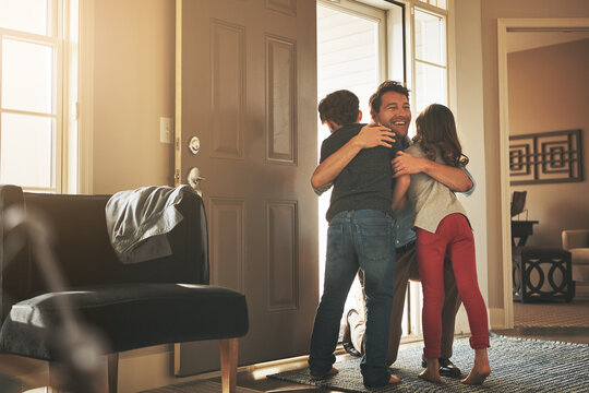 Home, love and a father hugging his kids after arriving through the front door after work during the day. Greeting, family or children with a man holding his son and daughter in the living room