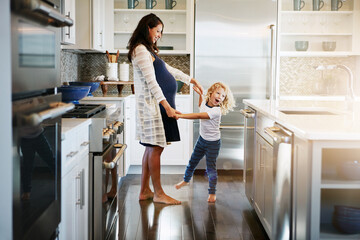 Happy family, pregnant woman with boy child and in kitchen at their home with lens flare. Mother with love or care, mother and cheerful parent with son bonding with dance in their house together - obrazy, fototapety, plakaty