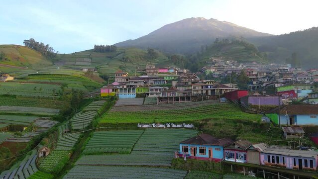 Aerial view of text "Selamat Datang di Dusun Butuh" or "Welcome to Butuh Village" installed at the entrance of Nepal Van Java with  in clear weather - 4K aerial video