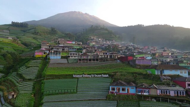 Aerial view of text "Selamat Datang di Dusun Butuh" or "Welcome to Butuh Village" at the entrance of Nepal Van Java with in sunny morning - 4K aerial video
