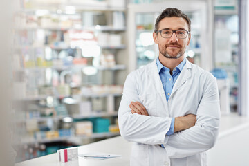 Healthcare, crossed arms and portrait of a male pharmacist standing in a pharmacy clinic. Pharmaceutical, medical and mature man chemist with confidence by the counter of medication store dispensary. - obrazy, fototapety, plakaty