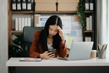 Asian woman feeling migraine head strain.Overworked businesswoman financier while working on laptop and tablet at office.
