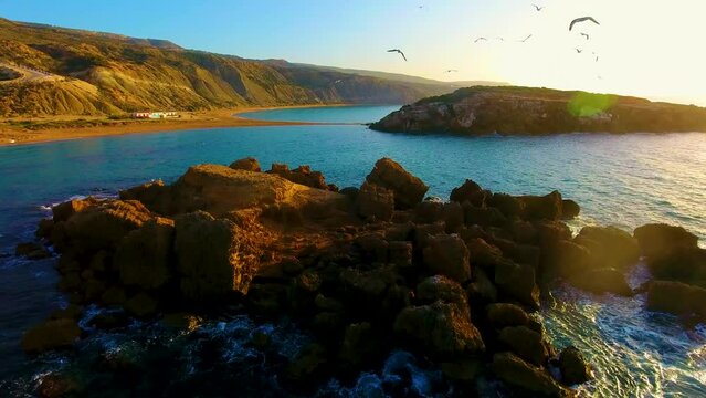 a rock in the middle of the sea full of seagulls at sunset in oran