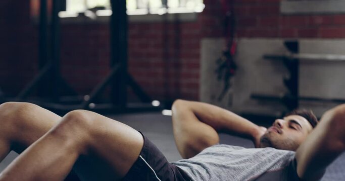 Fitness, training and a man doing situps at the gym for exercise, health and body goals. Serious, wellness and an athlete doing a workout routine for strength, cardio and sports for wellbeing