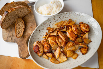 Quail breast with  sliced pear on plate, rice in bowl, bread on table.