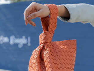 Woman holding a bright orange textured leather bag in her hand