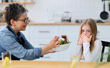 Mom tries to feed the child with vegetables, the girl closes her mouth and refuses to eat.