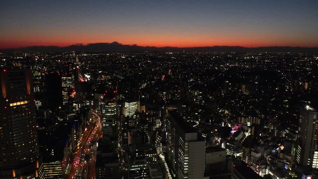 TOKYO, JAPAN : Aerial sunrise CITYSCAPE of TOKYO and MOUNT FUJI. View of rising sun and buildings around Shibuya. Japanese urban city life and nature concept. Long time lapse video, night to morning.