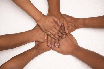 Fototapeta na wymiar Top view of diverse people putting their hands together on white background. Stack of different hands.Group of friend hands together joining big business project.Unity and teamwork concept.