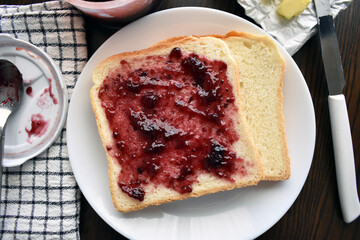Raspberry jam on sliced bread on a white plate.  