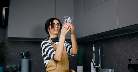 Young caucasian woman takes out clean crystal drinking glasses from dishwasher machine. Easy housework with kitchen appliances concept.