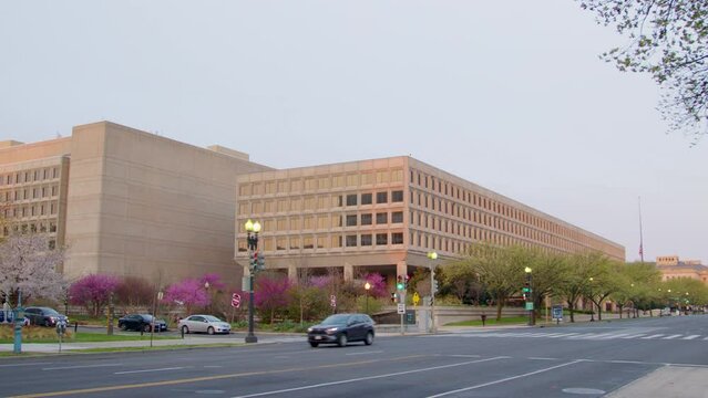 The camera pans right across Independence Avenue in Washington DC from the Department of Energy to the Smithsonian. The American flag stands at half-mast.