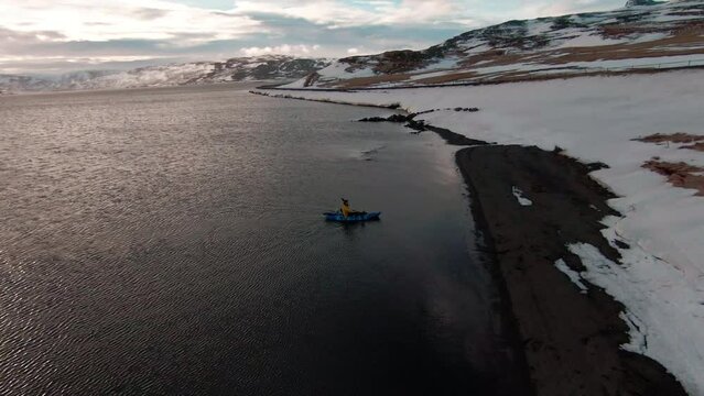 Fpv flying during sunset. Man rowing blue kayak to the shore 