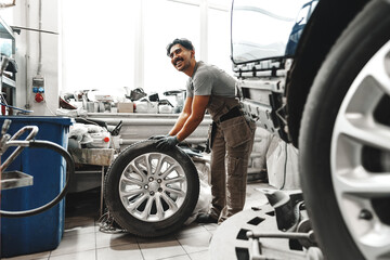 Obraz na płótnie Canvas Mechanic pushing a car tire in car service