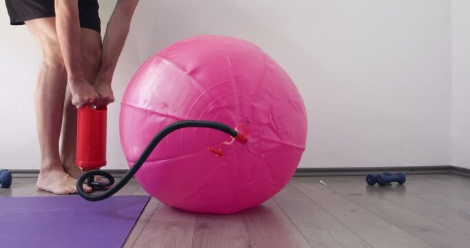 Man inflating fitness ball using hand pump at home, 