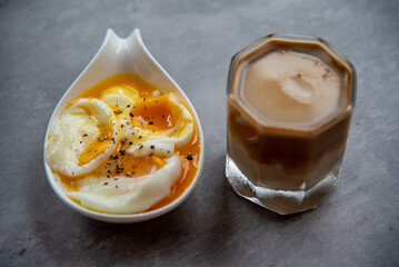 Dirty coffee in a clear glass with hard-boiled eggs in a white cup
