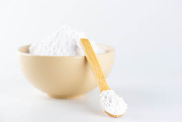 White powdered tapioca starch in a wooden spoon and bowl, cassava root powder.