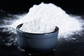 Tapioca starch in a bowl on a black background, dry cassava root.