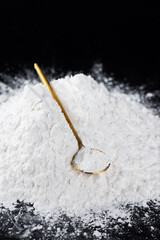 Heap of tapioca starch with spoon on a black background, dry cassava root.
