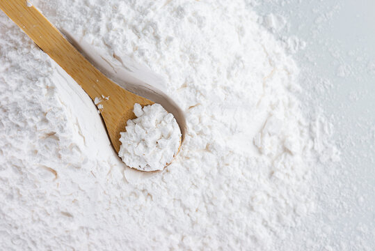 Organic white tapioca starch in a wooden spoon, dry cassava root.