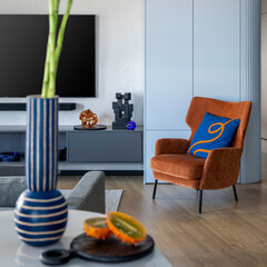 Interior design of living room interior with big tv, orange armchair, patterned pillow, wooden...
