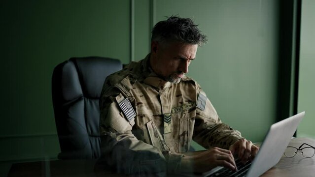 Soldier working with laptop in home. Everyday life of a military man in reserve. Work and communication online