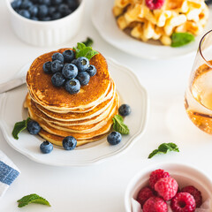Summer breakfast. Homemade baked ricotta pancakes and Belgian waffles with fresh berries on white wooden table